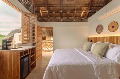 a bedroom with a large bed and a kitchen at Islawa Soy Local - Isla Privada in Baru