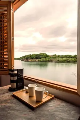 two cups of coffee on a window sill with a view of a river at Islawa Soy Local - Isla Privada in Baru