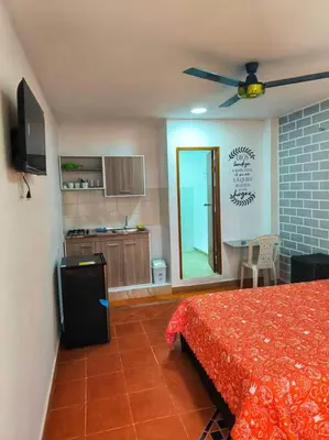 a bedroom with a red bed and a kitchen at Apartaestudios la terraza 2 in Sincelejo