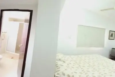 a white bedroom with a bed and a mirror at campestre, naturaleza, confort, familiar in Turbaco