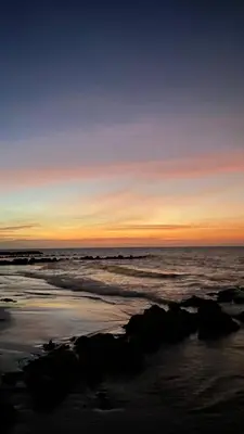 a sunset over the ocean with rocks on the beach at Cabaña Azores, Barú, Cartagena in Baru