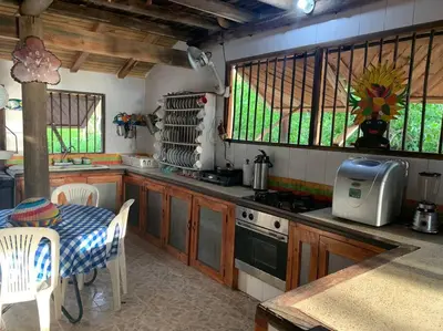 a kitchen with a table and a stove and some chairs at Cabaña Azores, Barú, Cartagena in Baru