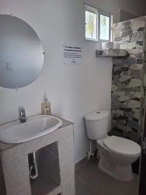 a bathroom with a sink and a toilet and a mirror at Cabañas Ana Sofía in San Antero