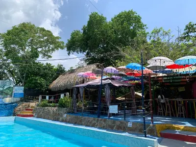 a resort with umbrellas and a swimming pool at Restaurante y Ecohostal Casa Loma in Chorrera