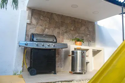 a grill in a backyard with a stone wall at Ledymar Chalet in Cartagena de Indias