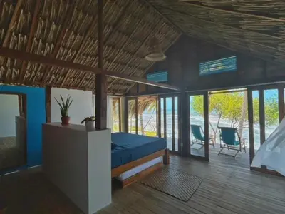 a bedroom with a blue bed in a room with windows at Entre Palmas Cabañas in Moñitos
