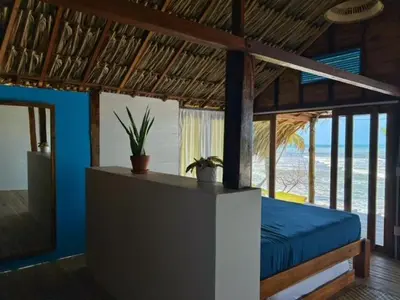 a bedroom with a bed with a view of the beach at Entre Palmas Cabañas in Moñitos