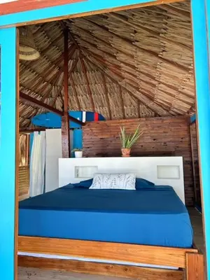a bedroom with a blue bed with a wooden ceiling at Entre Palmas Cabañas in Moñitos