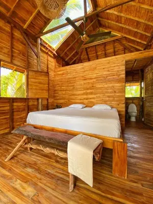 a bedroom with a bed and a bench in a room at Entre Palmas Cabañas in Moñitos