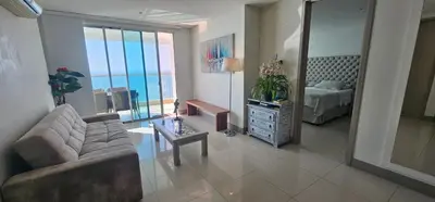 a living room with a couch and a bed and a table at Lujo frente a la playa in Cartagena de Indias