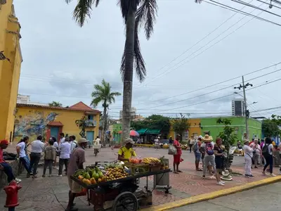 a group of people standing in a street with a cart of fruit at Hospedaje Doña Argenida in Cartagena de Indias