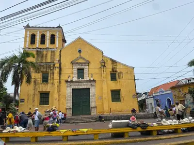 an old yellow building with people standing in front of it at Hospedaje Doña Argenida in Cartagena de Indias