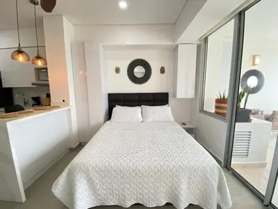 a white bedroom with a bed and a kitchen at Aparta suite Fantástique in Cartagena de Indias