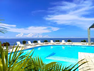 a swimming pool with chairs and the ocean in the background at Apartamento VIP - Con vistas al Mar y Playa in Santa Marta