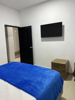 a bedroom with a bed with a blue blanket and a tv at Casa Torices Real 12 in Cartagena de Indias