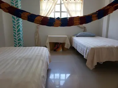 two beds in a room with a hammock between them at Alojamiento Serena Tu Casa en la Playa in Cartagena de Indias