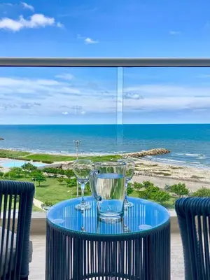 a table with two wine glasses on a balcony with the ocean at Suite moderna con vista al mar y parque CB 814 in Cartagena de Indias