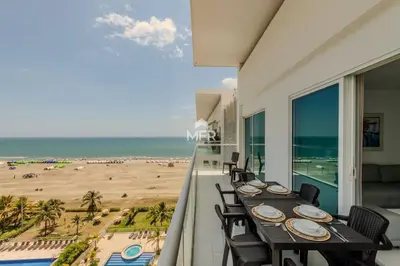 a balcony with a table and chairs and the beach at Edificio Morros 3, Beachfront & 2 Bedrooms by Inmobiliaria MFR in Cartagena de Indias