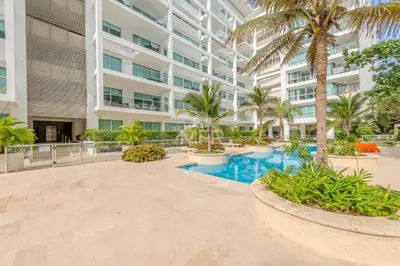 an exterior view of a building with a swimming pool and palm trees at Edificio Morros 3, Beachfront & 2 Bedrooms by Inmobiliaria MFR in Cartagena de Indias