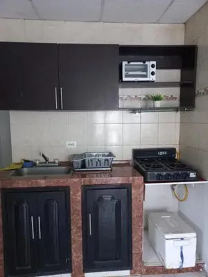 a kitchen with black cabinets and a stove and a sink at Apartamento hostal oasis in Puerto Colombia