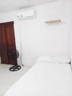 a room with a bed and a door and a chair at Apartamento hostal oasis in Puerto Colombia