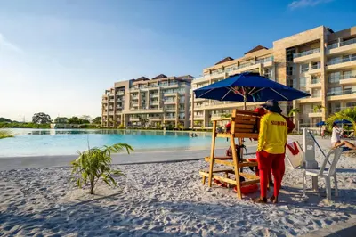 a man standing on a beach under an umbrella at Apartamento con laguna de aguas cristalinas in Cartagena de Indias
