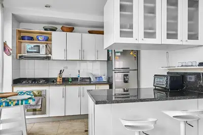 a kitchen with white cabinets and a counter with stools at Ocean Luxe Morros in Cartagena de Indias