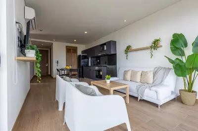 a living room with white furniture and a kitchen at Cabrero Centro Tropical - Con vista al mar in Cartagena de Indias