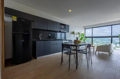 a kitchen with a black refrigerator and a table and chairs at Cabrero Centro Tropical - Con vista al mar in Cartagena de Indias