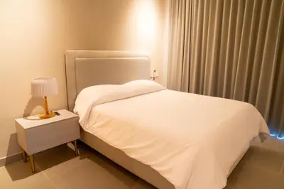 a bedroom with a white bed and a lamp on a night stand at Lujoso Apartamento Baia Kristal in Cartagena de Indias