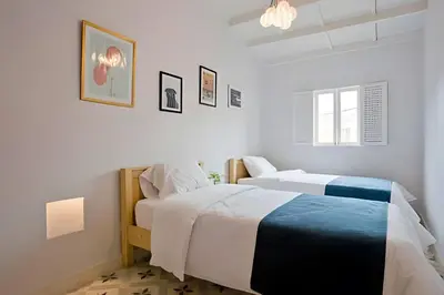 a white bedroom with two beds and a chandelier at Apartamento Bovedas, Aldaba Selection in Cartagena de Indias