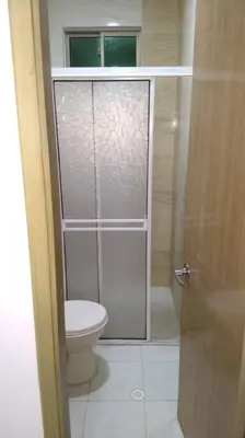 a bathroom with a toilet and a glass shower door at Apto 202, área mtana de Barranquilla in Soledad