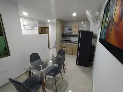 a kitchen with a glass table and chairs and a refrigerator at Apto 202, área mtana de Barranquilla in Soledad