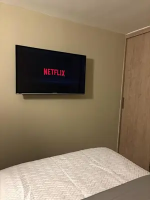 a flat screen tv on a wall above a bed at Apartamento en Alameda Barranquilla in Barranquilla