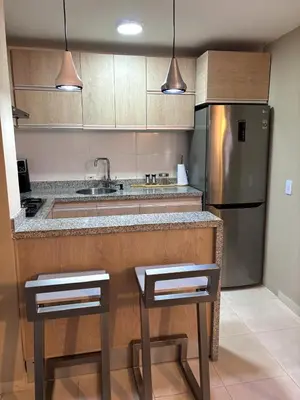 a kitchen with a stainless steel refrigerator and two bar stools at Apartamento en Alameda Barranquilla in Barranquilla