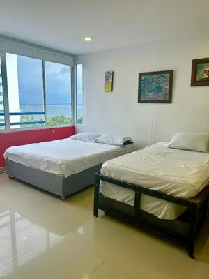 two beds in a bedroom with a view of the ocean at 1C-AL2J APARTAMENTO DE 1 ALCOBA CERCA AL MAR CON AIRE ACONDICIONADO PISCINA Y WIFi in Cartagena de Indias