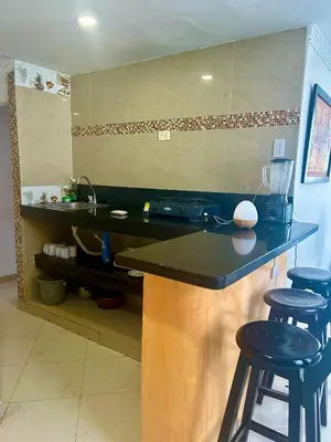 a kitchen with a counter with stools and a sink at 1C-AL2J APARTAMENTO DE 1 ALCOBA CERCA AL MAR CON AIRE ACONDICIONADO PISCINA Y WIFi in Cartagena de Indias