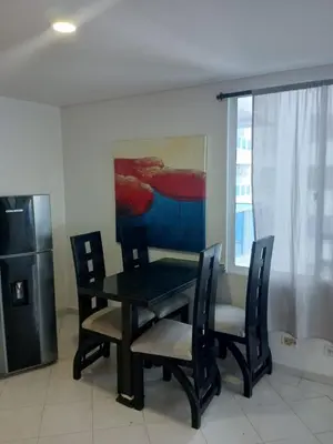 a dining room with a table and chairs and a painting at 1C-AL2J APARTAMENTO DE 1 ALCOBA CERCA AL MAR CON AIRE ACONDICIONADO PISCINA Y WIFi in Cartagena de Indias