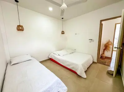 two beds in a room with white walls and a mirror at Casa de Playa ROSANI in Coveñas