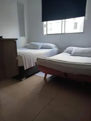 a bedroom with two beds and a dresser and two windows at Jardin imperial, habitaciones economica en apartamento familiar zona tranquila WIFI in Cartagena de Indias