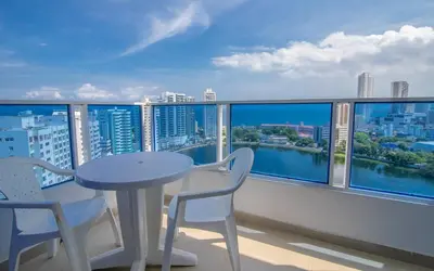 a table and chairs on a balcony with a view of the city at 2C-AL2E APARTAMENTO DE 2 ALCOCABAS CERCA AL MAR CON AIRE ACONDICIONADO, PISCINA Y WIFi in Cartagena de Indias