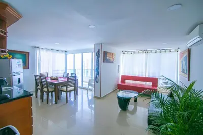 a living room with a table and a red couch at 2C-AL2E APARTAMENTO DE 2 ALCOCABAS CERCA AL MAR CON AIRE ACONDICIONADO, PISCINA Y WIFi in Cartagena de Indias