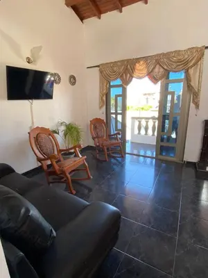 a living room with a couch and chairs and a tv at Cabaña Tolu in Santiago