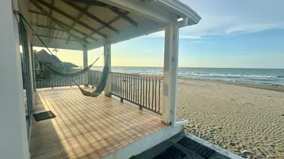 a porch with a hammock on the beach at Hermosa Cabaña Frente Al Mar in San Bernardo del Viento
