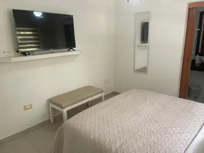 a bedroom with a bed and a bench and a tv at Italia boutique Apt 2 in Barranquilla