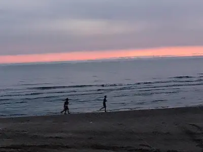two people walking on the beach at sunset at Hostal Playa Descalzo in Cartagena de Indias