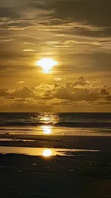 a sunset on the beach with the sun setting at Hostal playa descalzo in La Boquilla
