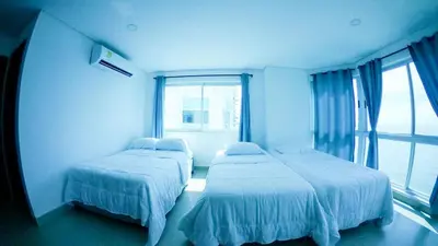 two beds in a room with a large window at Tu Pent-House Con Vista al Mar! in Cartagena de Indias