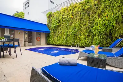 a patio with blue chairs and a swimming pool at Varanasi Hotel Boutique Aeropuerto in Cartagena de Indias