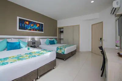 a hotel room with two beds and a desk at Varanasi Hotel Boutique Aeropuerto in Cartagena de Indias
